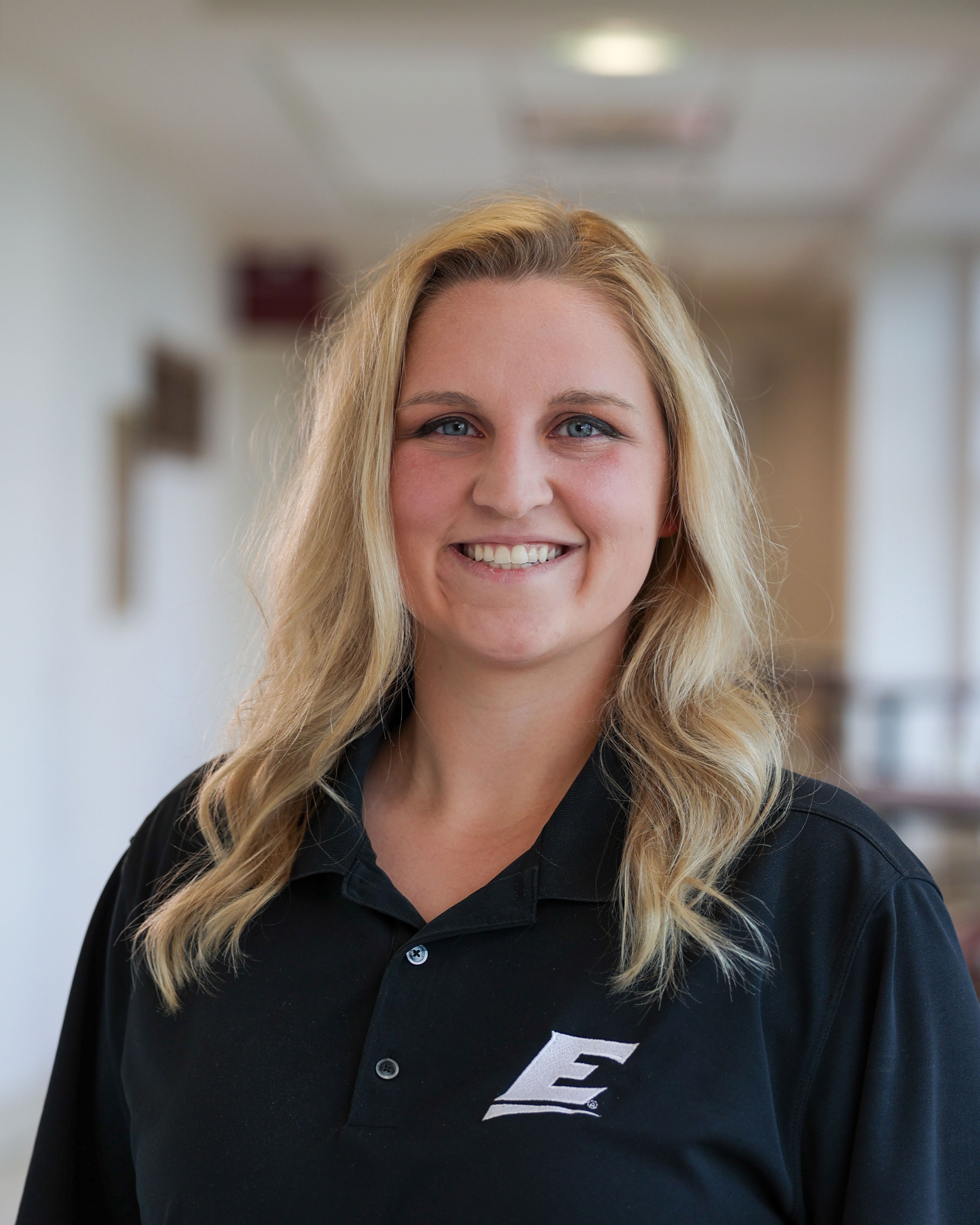 women smiling with a eku polo shirt on 