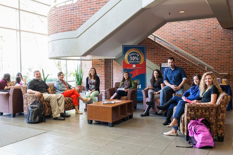 Group of students posing and smiling at the camera in a lounging area