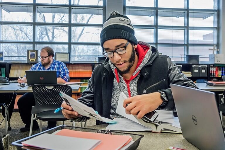 Student looking through papers in a busy room