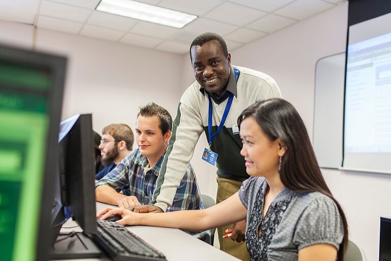 Guy helping student at computer