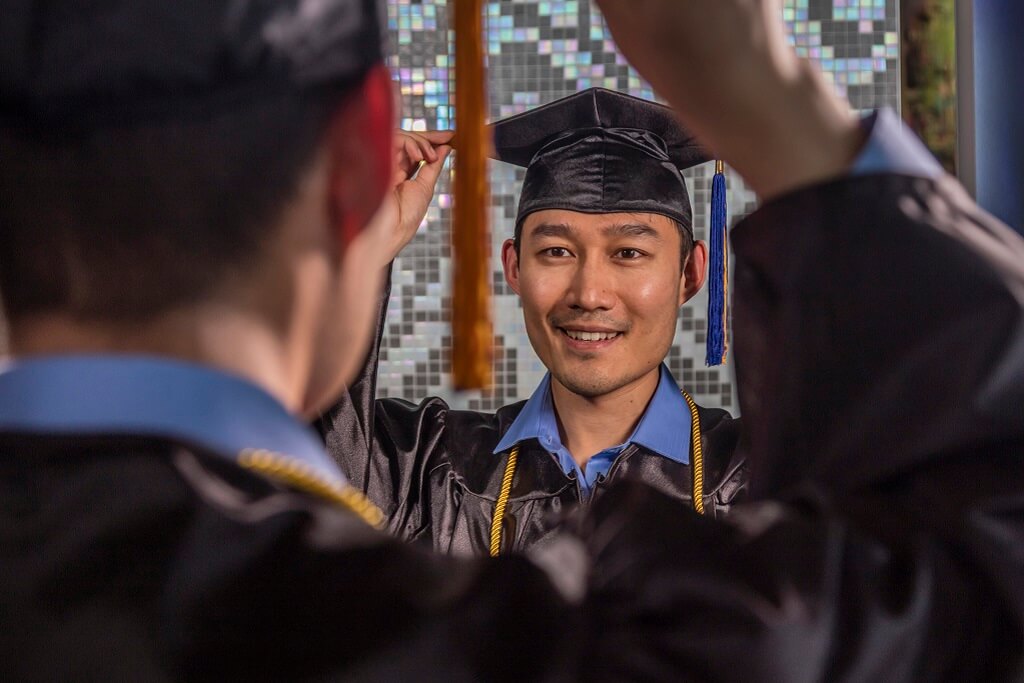 guy in graduation cap and gown looking in mirror