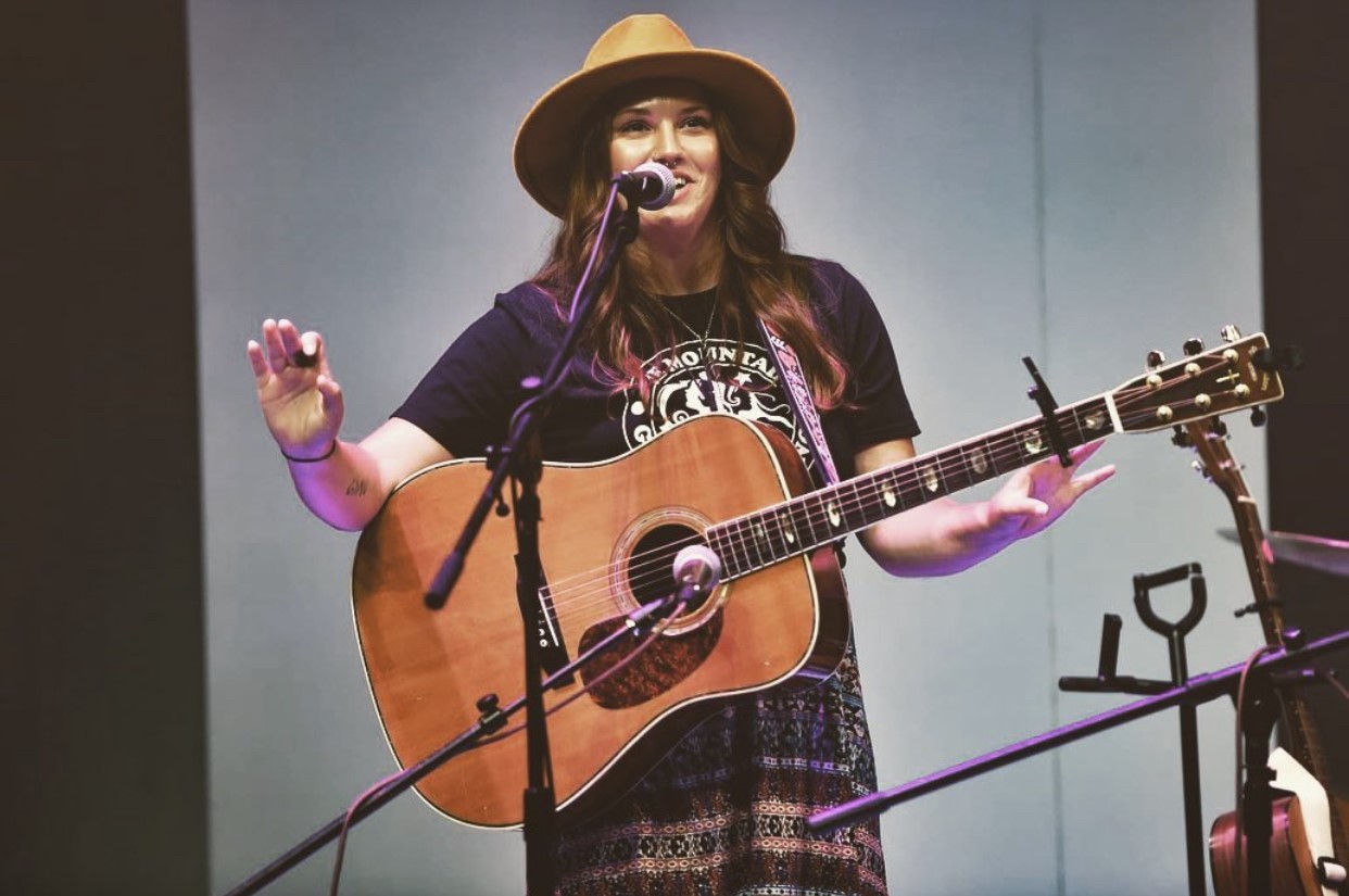 girl in front of a microphone with a guitar